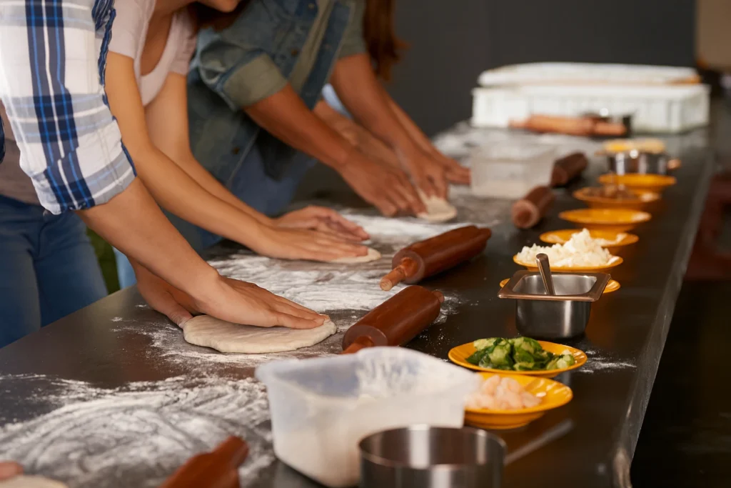 Friends gathered around a table making pizzas