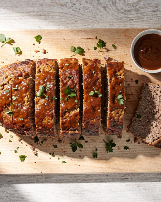 A perfectly cooked meatloaf recipe on a rustic cutting board, drizzled with glaze and ready to be sliced.