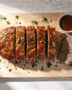 A perfectly cooked meatloaf recipe on a rustic cutting board, drizzled with glaze and ready to be sliced.