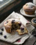 A stack of warm, perfect blueberry muffins from the ultimate moist blueberry muffin recipe on a rustic wood table.