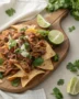 An overhead shot of the ultimate pulled pork nachos recipe, steaming hot and loaded with toppings.