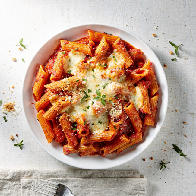 A golden-brown pan of baked ziti fresh from the oven, with stretchy melted cheese and rich tomato sauce.