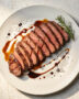 A close-up shot of grilled flank steak marinated in a balsamic vinegar flank steak marinade, glistening with flavor.