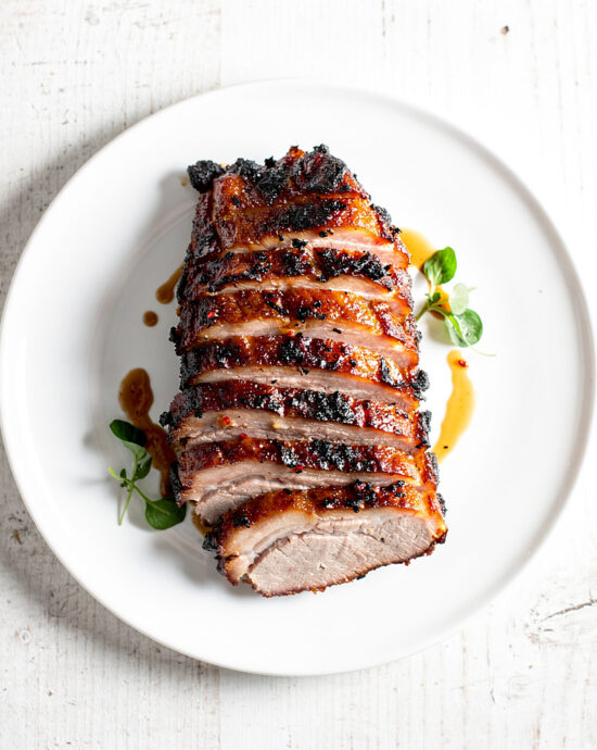 A perfectly cooked and pulled bbq pork shoulder, glistening with juices, on a rustic wooden cutting board.