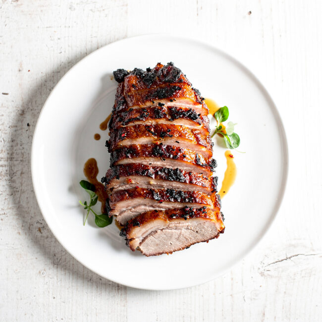 A perfectly cooked and pulled bbq pork shoulder, glistening with juices, on a rustic wooden cutting board.