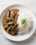 A creamy and inviting bowl of beef stroganoff brazil served with white rice and crispy potato sticks.
