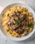 A top-down view of the finished beef stroganoff recipe, showcasing creamy sauce, tender beef, and herbs over egg noodles.