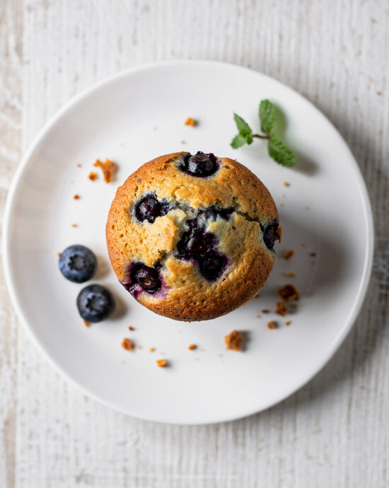 A batch of freshly baked blueberry muffins from the best blueberry muffin recipe, with a golden crumb topping.