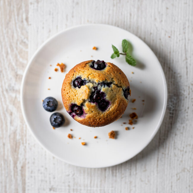 A batch of freshly baked blueberry muffins from the best blueberry muffin recipe, with a golden crumb topping.