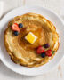 A stack of golden, delicate crepes from the best crepe recipe, drizzled with honey and berries.