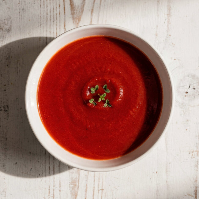A velvety bowl of the best tomato soup brand, topped with fresh basil and a swirl of cream.
