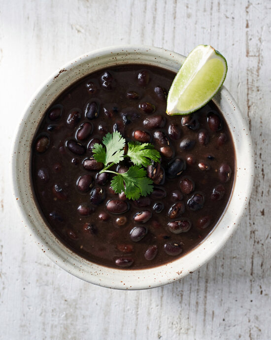 A rich and hearty bowl of black bean soup brazilian topped with fresh cilantro and served with rice.