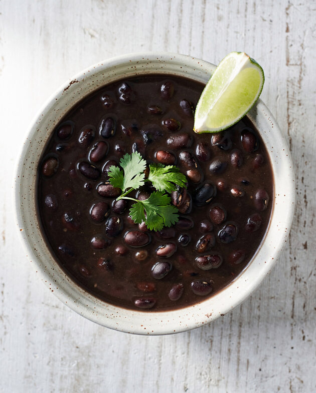 A rich and hearty bowl of black bean soup brazilian topped with fresh cilantro and served with rice.