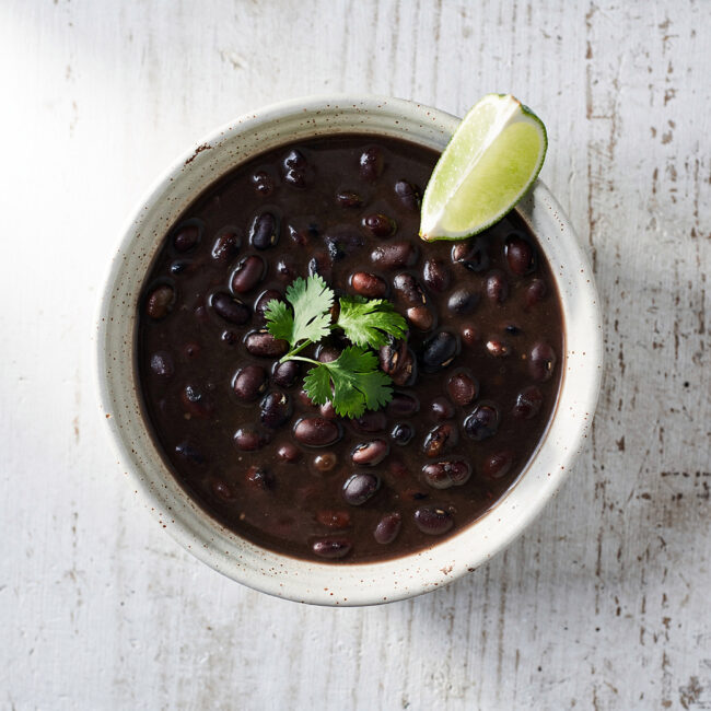 A rich and hearty bowl of black bean soup brazilian topped with fresh cilantro and served with rice.