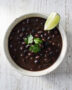 A rich and hearty bowl of black bean soup brazilian topped with fresh cilantro and served with rice.