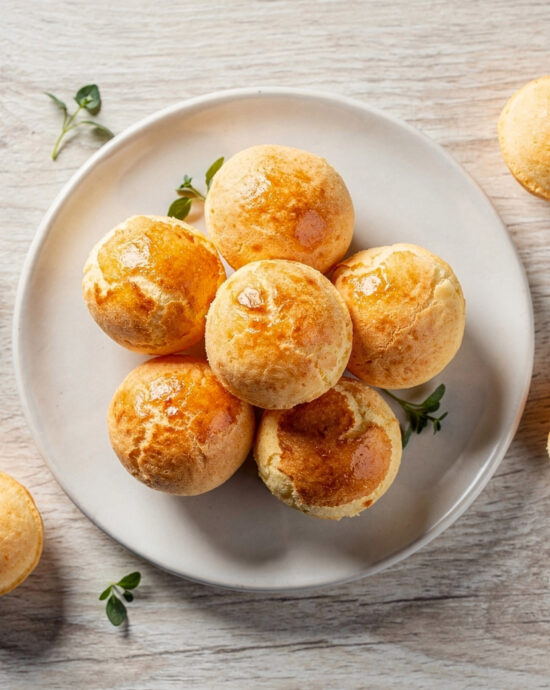 Golden-brown puffs of Brazilian bread cheese recipe fresh from the oven on a rustic wooden board.