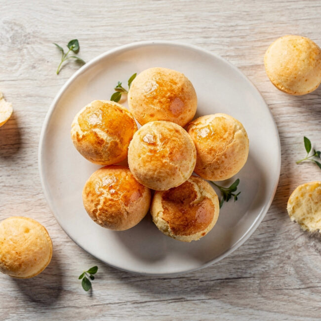 Golden-brown puffs of Brazilian bread cheese recipe fresh from the oven on a rustic wooden board.