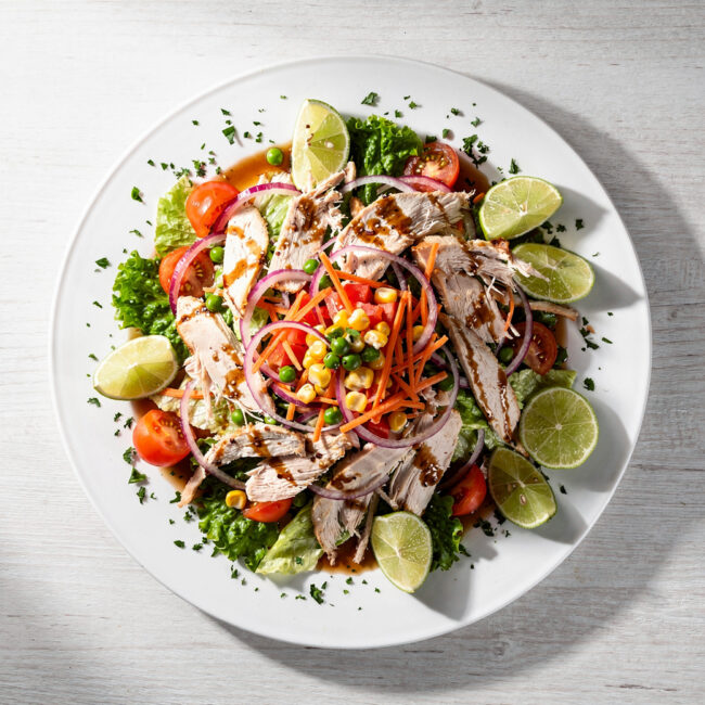 A colorful and crunchy Brazilian chicken salad (salpicão) served on a white platter.