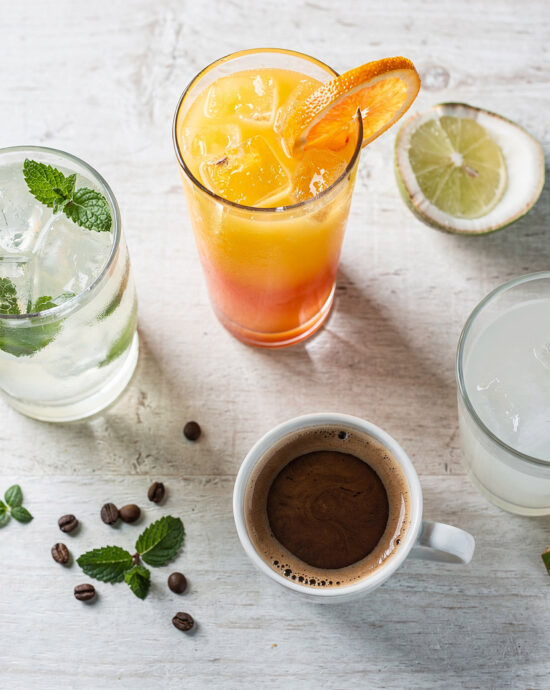 A vibrant collection of authentic brazilian drinks, from green juices to golden caipirinhas, beautifully styled on a rustic wood table.