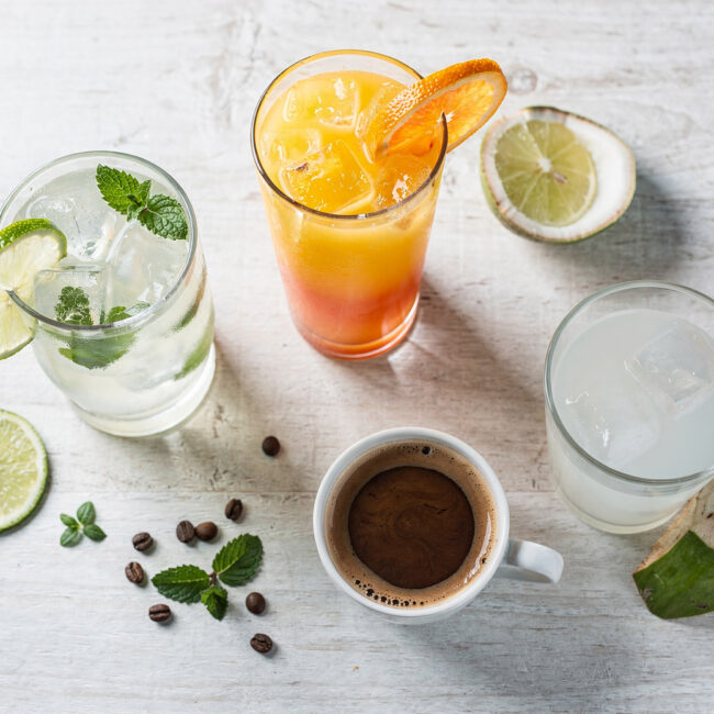 A vibrant collection of authentic brazilian drinks, from green juices to golden caipirinhas, beautifully styled on a rustic wood table.