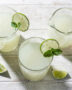 A frosty glass of creamy Brazilian limeade sits on a sun-drenched wooden table.