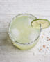 A frosty glass of Brazilian margarita with a salted rim, garnished with a lime wheel and a slice of fresh passion fruit.