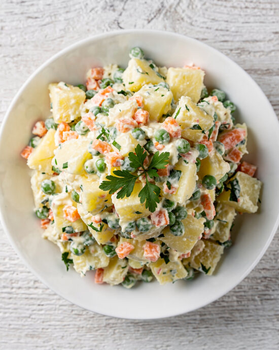 A vibrant bowl of traditional Brazilian potato salad, ready to be scooped and served at a festive gathering.