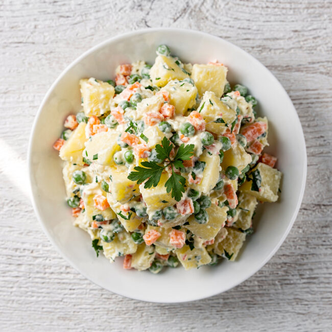 A vibrant bowl of traditional Brazilian potato salad, ready to be scooped and served at a festive gathering.