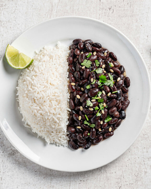 A vibrant, inviting bowl of perfectly cooked brazilian rice and beans, served side-by-side on a rustic wooden table.
