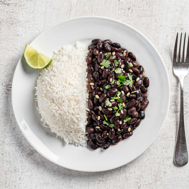 A vibrant, inviting bowl of perfectly cooked brazilian rice and beans, served side-by-side on a rustic wooden table.