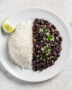 A vibrant, inviting bowl of perfectly cooked brazilian rice and beans, served side-by-side on a rustic wooden table.