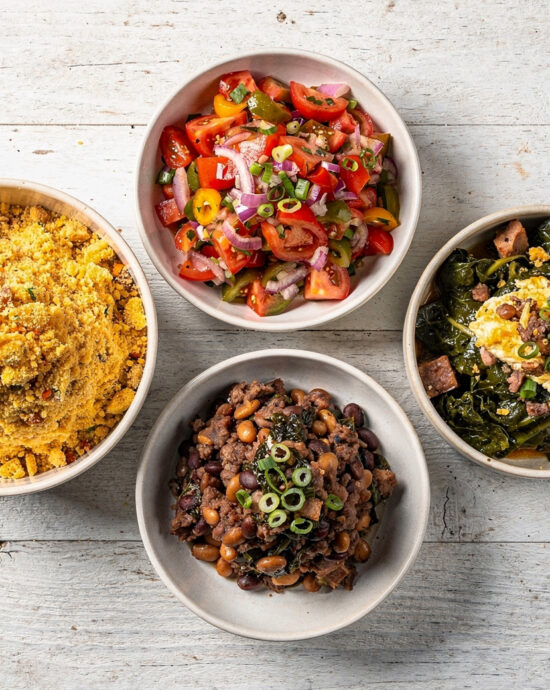 An overhead view of a vibrant spread showcasing essential brazilian side dishes including farofa, vinagrete salsa, and feijão tropeiro beans.