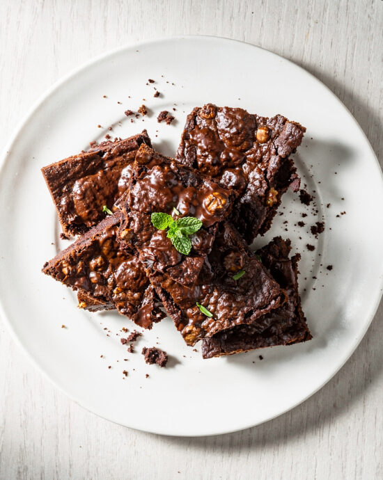 A rustic top-down shot of homemade chocolate brownie brittle on a wooden board.