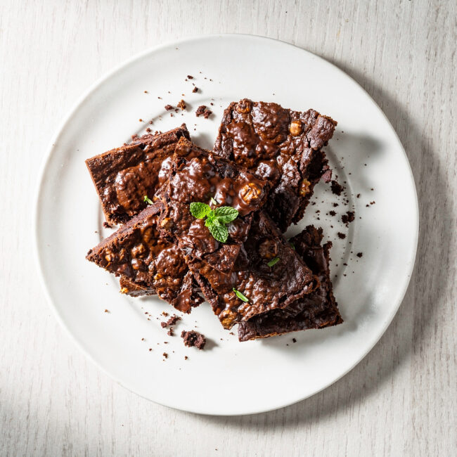 A rustic top-down shot of homemade chocolate brownie brittle on a wooden board.