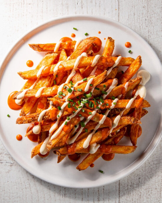 A heaping platter of crispy buffalo fries drizzled with blue cheese dressing sits ready to be devoured.