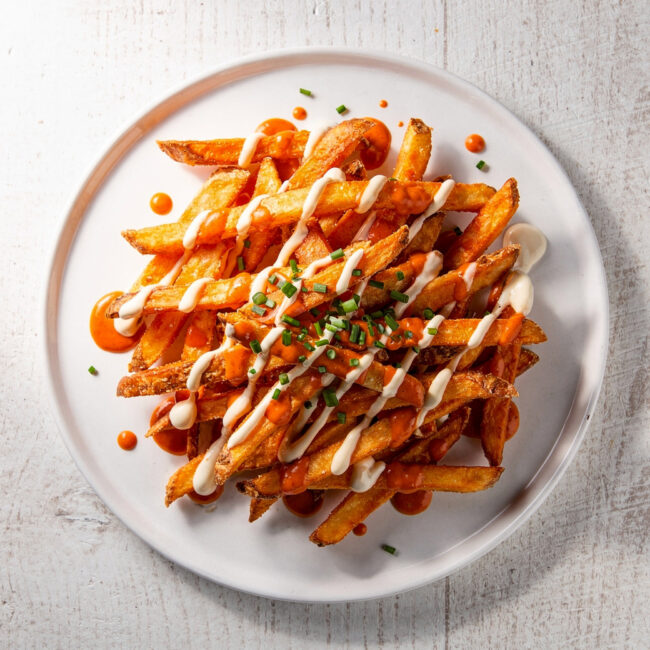 A heaping platter of crispy buffalo fries drizzled with blue cheese dressing sits ready to be devoured.