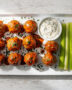 A glossy, inviting platter of golden-brown buffalo meatballs drizzled with sauce, ready for dipping.