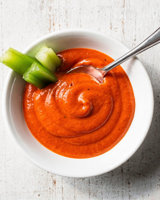 A glossy, vibrant homemade buffalo sauce drizzled over crispy chicken wings.