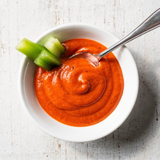 A glossy, vibrant homemade buffalo sauce drizzled over crispy chicken wings.