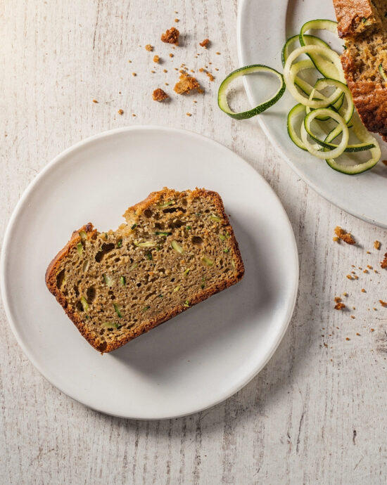 A beautifully baked loaf of cake mix zucchini bread, sliced to reveal its moist interior, resting on a rustic wooden board.
