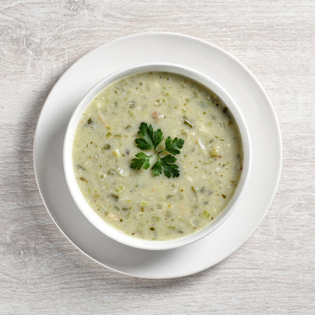 A creamy bowl of homemade-style soup made with Campbell's cream of celery soup, garnished with fresh herbs.