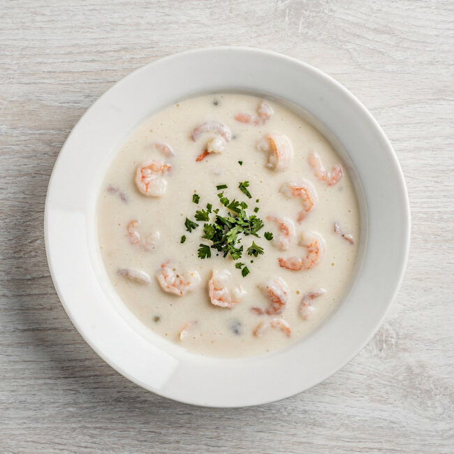 A creamy, inviting bowl of campbell's cream of shrimp soup garnished with fresh parsley, perfect for a cozy meal.