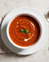 A beautifully styled bowl of homemade campbell's tomato basil soup on a rustic wooden table.
