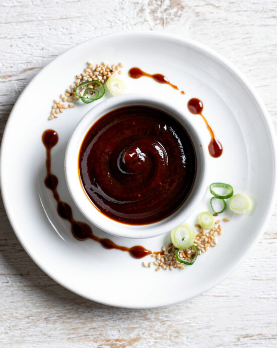 A glossy, deep red char siu sauce drizzled over succulent roast pork in a bowl.