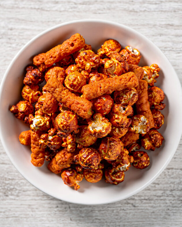 A close-up of a bowl of delicious cheetos flamin hot popcorn, coated in a vibrant orange cheese seasoning.