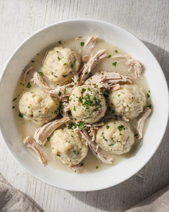 A steaming bowl of homemade chicken and dumplings with fluffy dumplings and tender chicken in a rich broth.