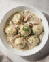 A steaming bowl of homemade chicken and dumplings with fluffy dumplings and tender chicken in a rich broth.