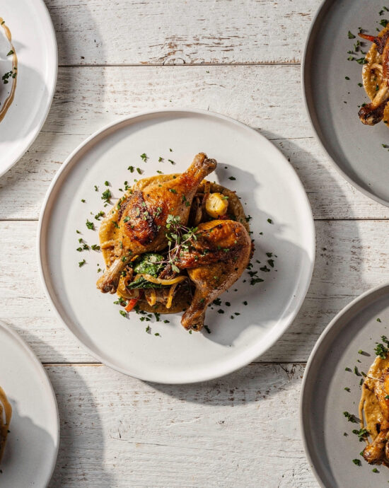 A delicious plate of herb-roasted chicken leg recipes served with fresh herbs and lemon wedges.