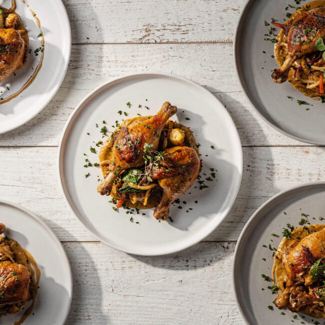 A delicious plate of herb-roasted chicken leg recipes served with fresh herbs and lemon wedges.