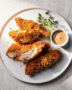 A heaping platter of golden-brown, crispy chicken strips on a wooden board, ready for dipping.